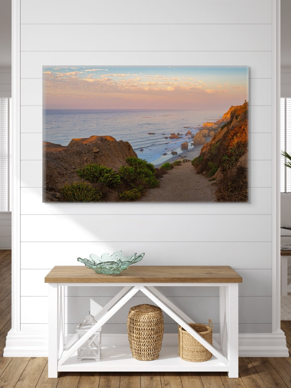 Canvas print of a coastal landscape above a wooden bench with decorative items.