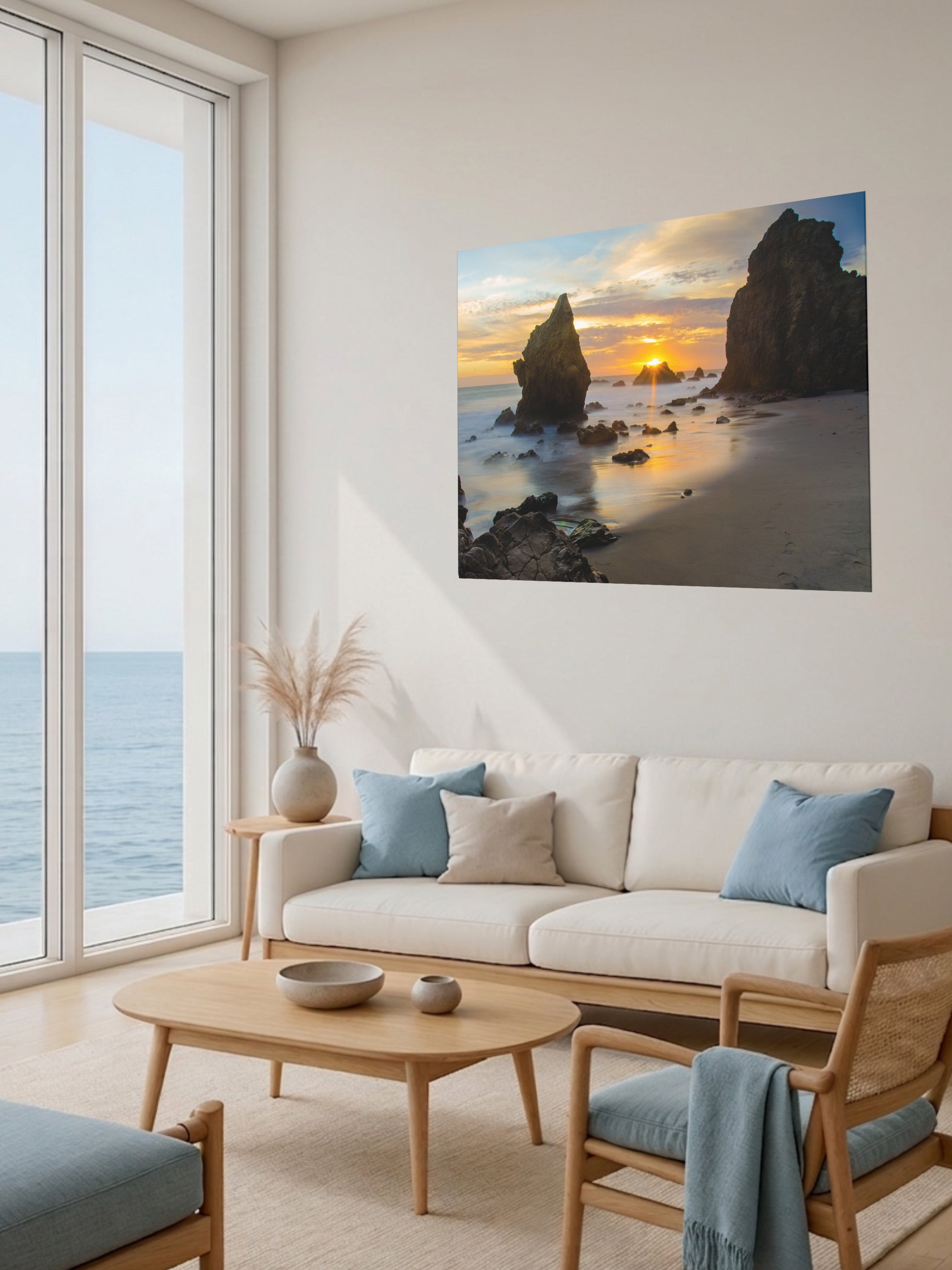 Modern living room with a large window, beige sofa, wooden coffee table, and an El Matador State Beach winter sunset with dramatic sea stacks and golden sunburst canvas print.