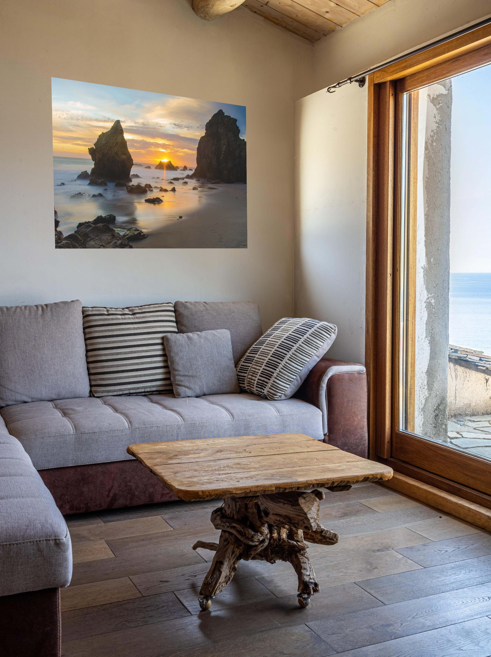 Living room with a gray sofa, wooden coffee table, and an El Matador State Beach winter sunset with dramatic sea stacks and golden sunburst canvas print.