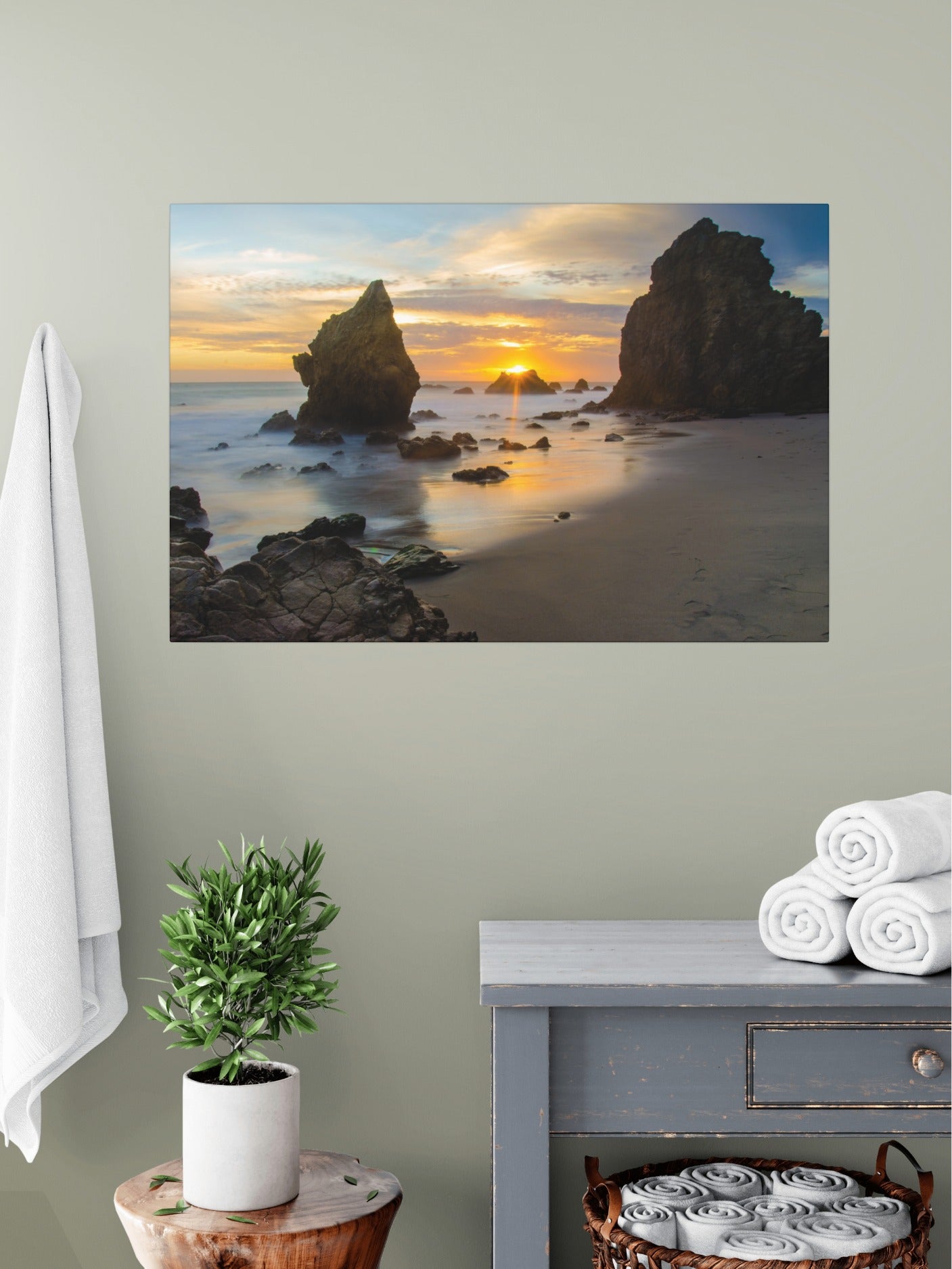 El Matador State Beach winter sunset with dramatic sea stacks and golden sunburst canvas print above a dresser with towels and a plant.