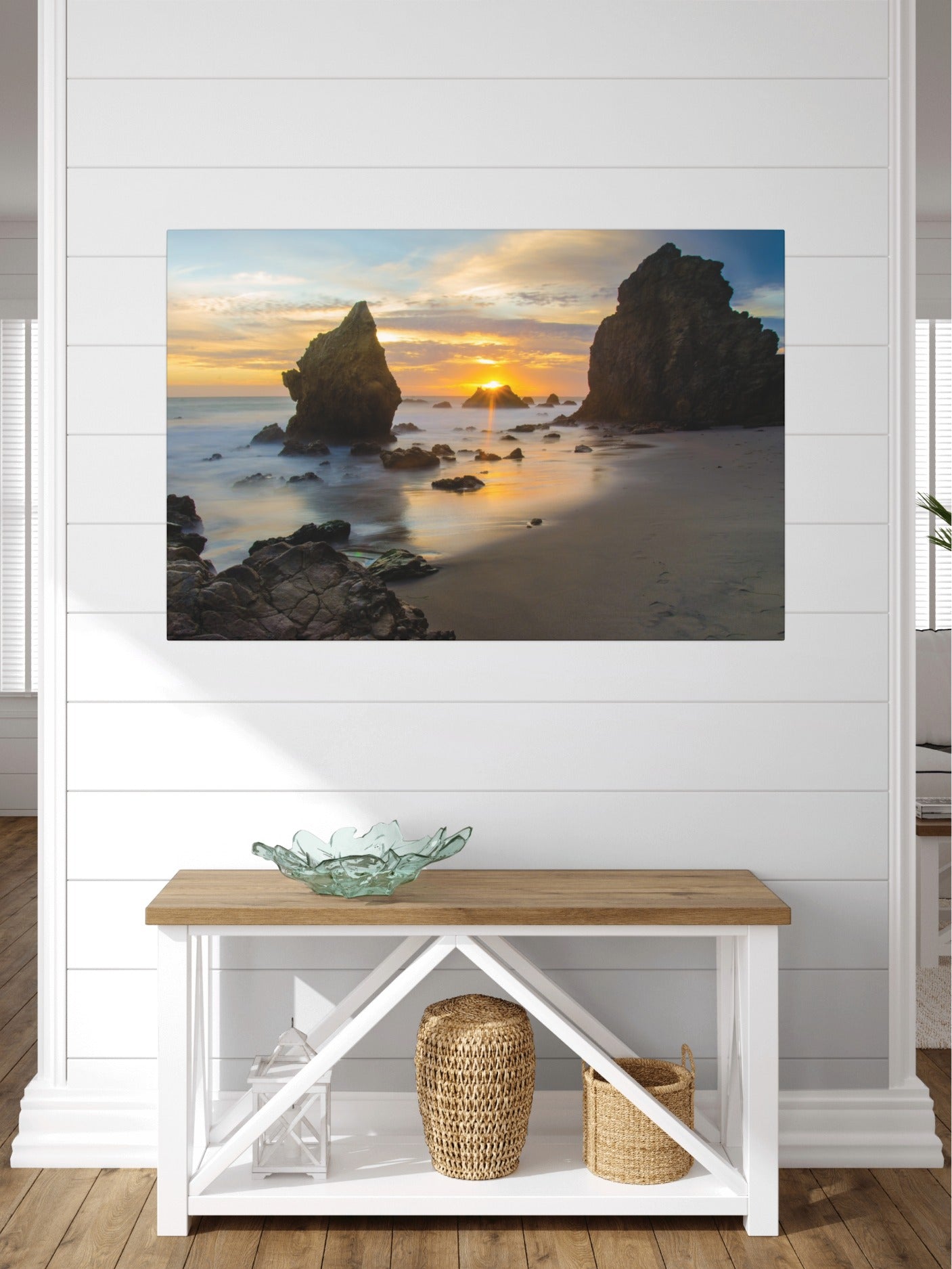 El Matador State Beach winter sunset with dramatic sea stacks and golden sunburst canvas print on a wall above a wooden bench with a glass bowl and baskets.