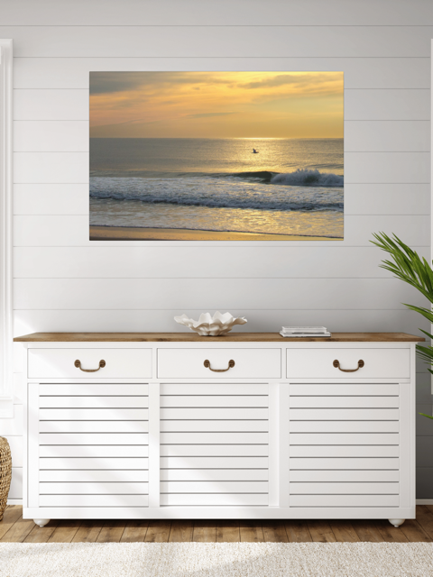 White storage cabinet with wooden top in a room with a canvas print of a bird in flight over the ocean at sunrise on the wall.