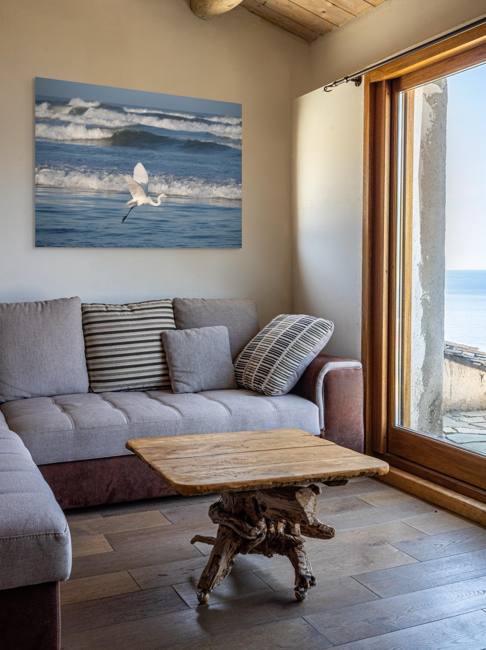 Living room with a gray sofa, wooden coffee table, and a large canvas print of a white egret in flight over the ocean on the wall.