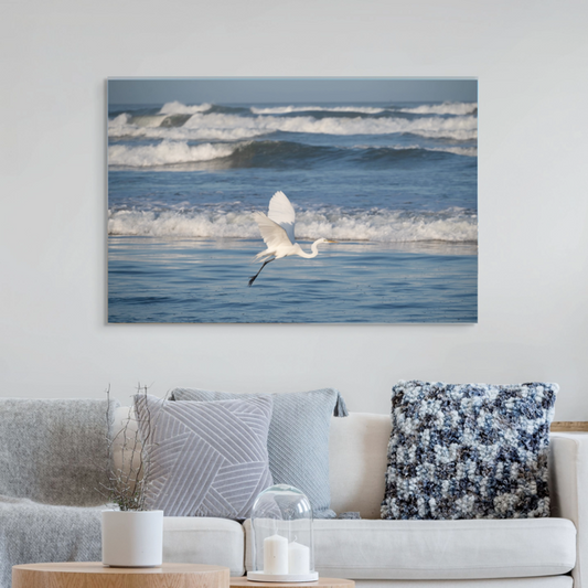 Living room with a large canvas print of a white egret in flight over the ocean on the wall.