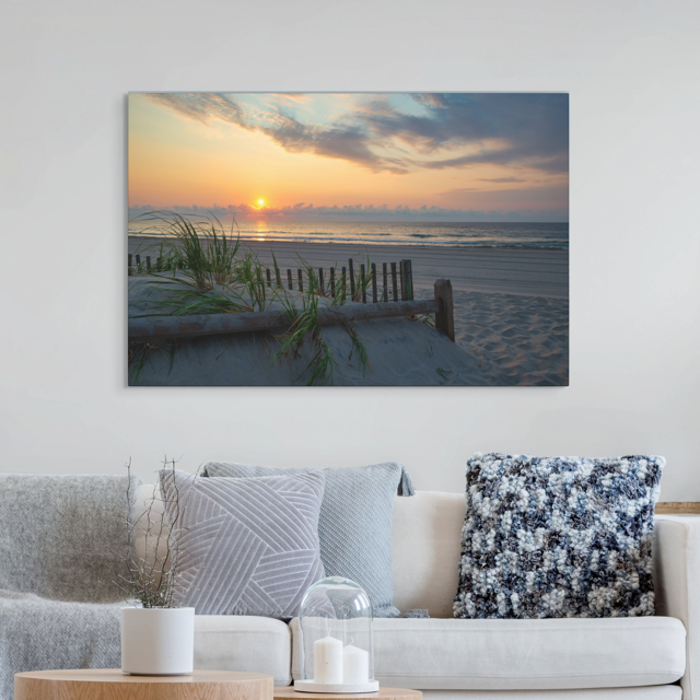 Living room with a large canvas print featuring a sunrise over the ocean as seen from behind the dunes on the Jersey Shore on the wall above a sofa.