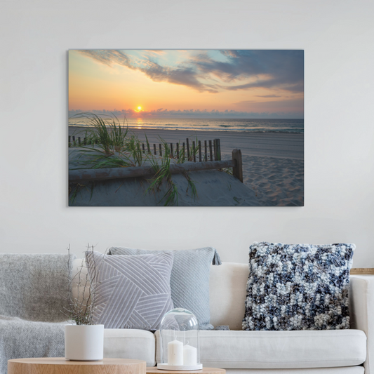 Living room with a large canvas print featuring a sunrise over the ocean as seen from behind the dunes on the Jersey Shore on the wall above a sofa.