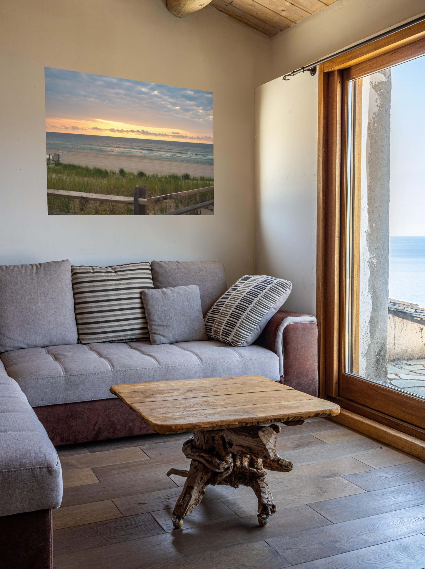 Living room with a gray sofa, wooden coffee table, and a canvas print of a Jersey Shore sunrise over the Atlantic Ocean with beach dunes and grass.
