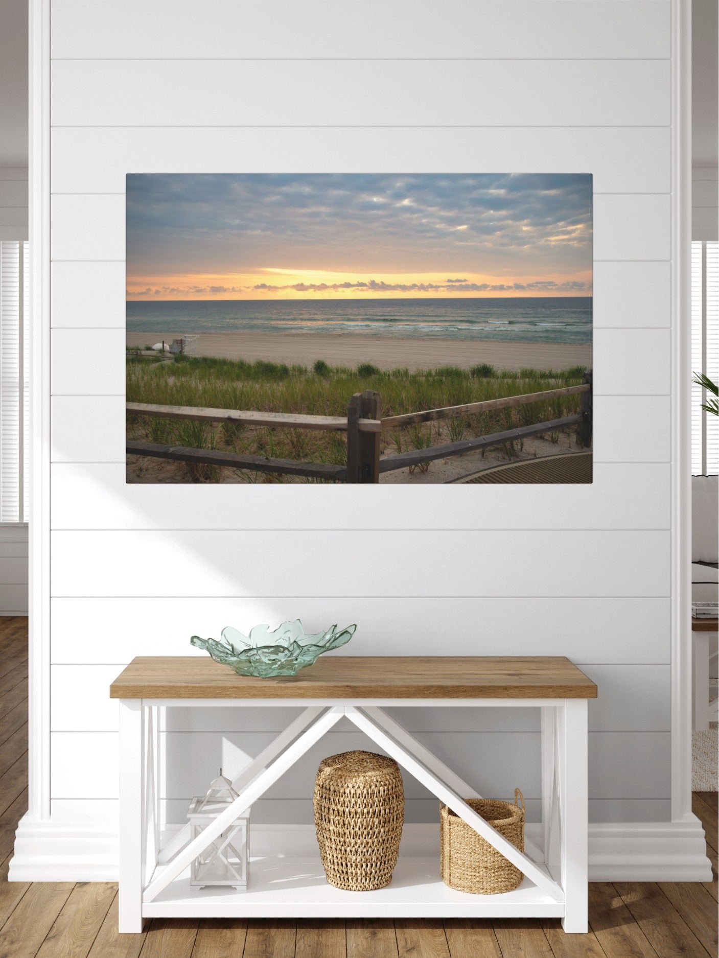 Canvas print of a Jersey Shore sunrise over the Atlantic Ocean with beach dunes and grass on a wall above a wooden bench with decorative items.