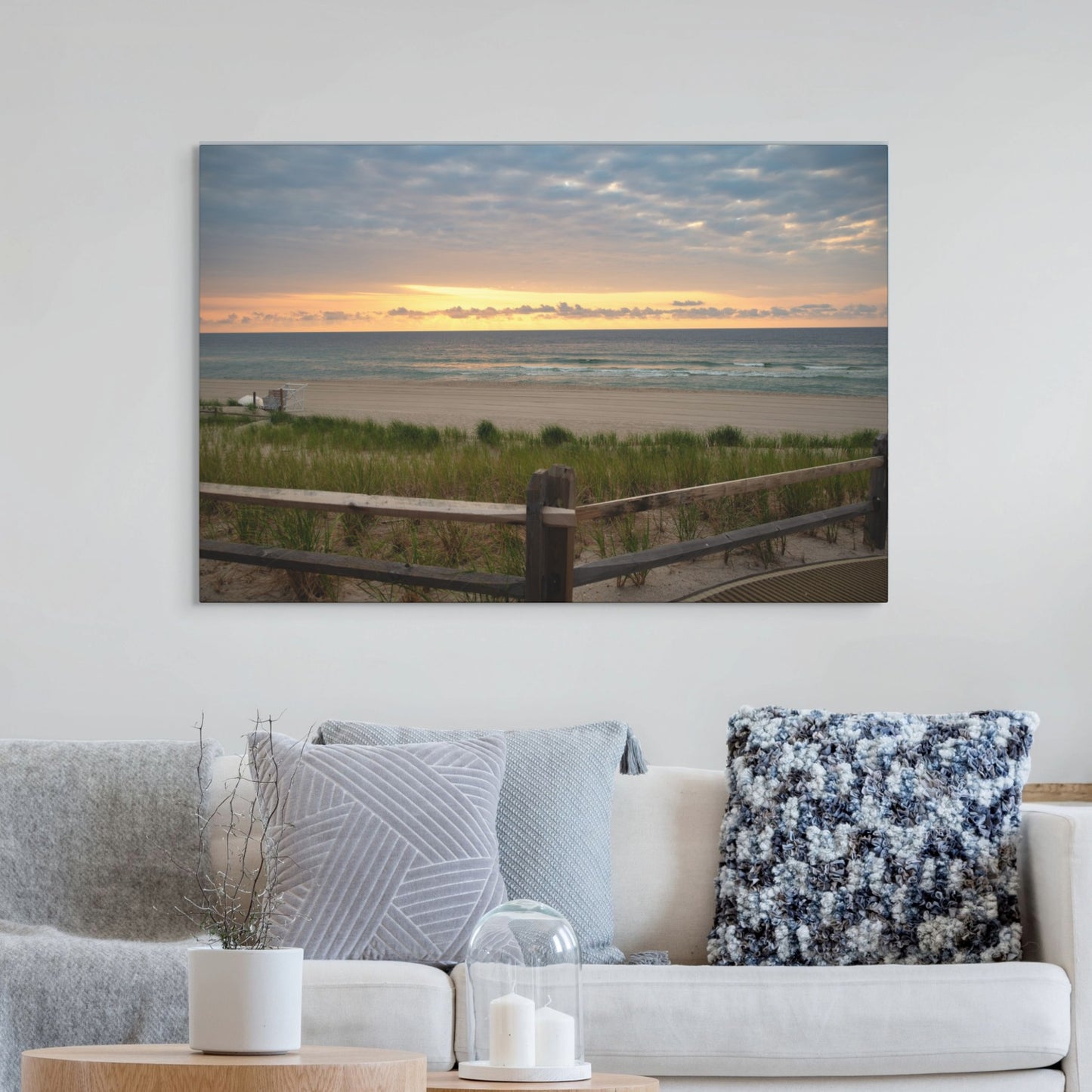Canvas print of a Jersey Shore sunrise over the Atlantic Ocean with beach dunes and grass hanging above a living room sofa with decorative pillows.