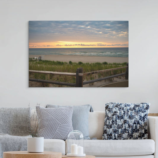 Canvas print of a Jersey Shore sunrise over the Atlantic Ocean with beach dunes and grass hanging above a living room sofa with decorative pillows.