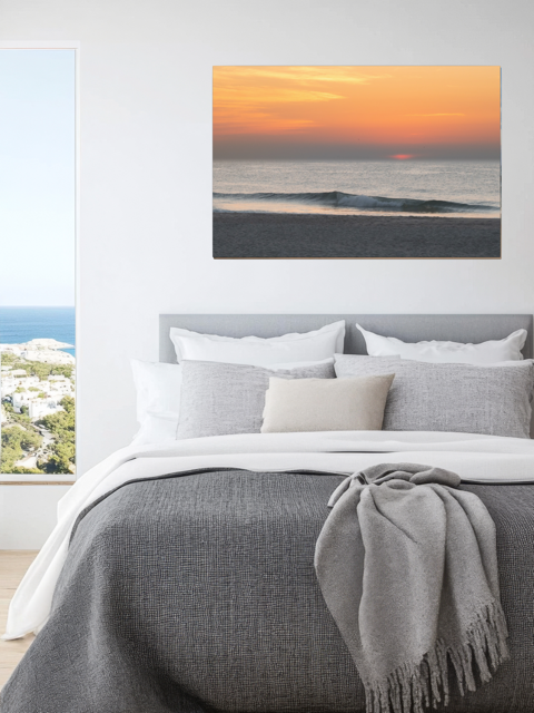 Bedroom with a large bed and a canvas print of a hazy sunrise over the ocean down the Jersey Shore on the wall.