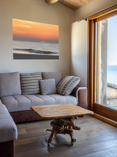 Living room with a gray sofa, wooden coffee table, and a canvas print of a hazy sunrise over the ocean down the Jersey Shore.