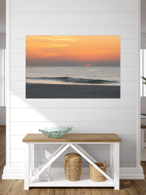 Canvas print of a hazy sunrise over the ocean down the Jersey Shore in a room with a wooden bench and decorative items.