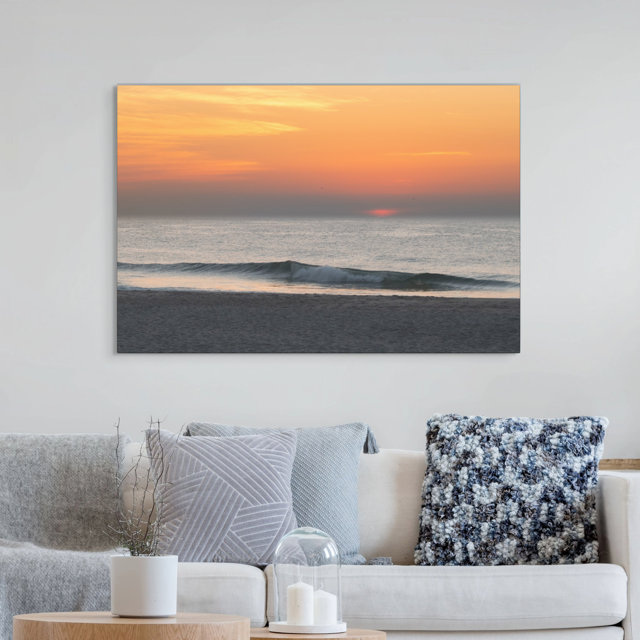 Sofa with decorative pillows and a scanvas print of a hazy sunrise over the ocean down the Jersey Shore on the wall