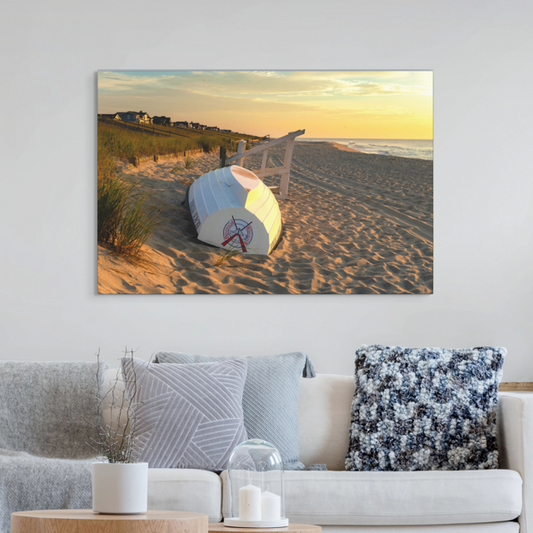 Canvas print of an overturned Jersey Shore Beach Patrol boat and lifeguard stand on the sand at sunrise with beach grass and rolling dunes on a wall above a sofa.