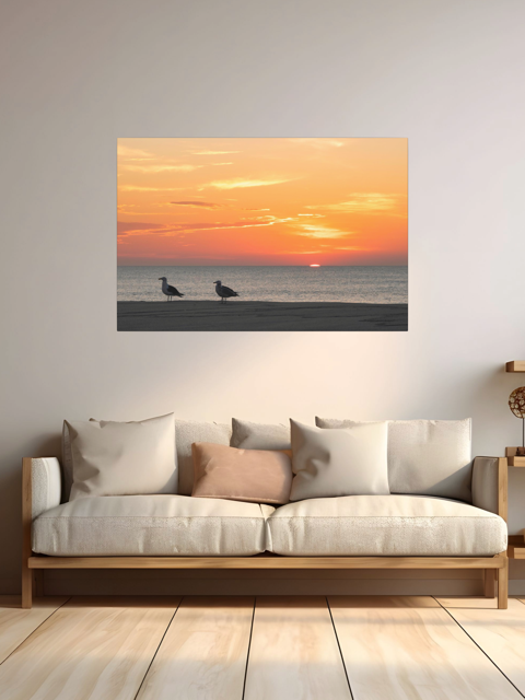 Sofa with a large wall art of two seagulls standing on a sandy Jersey Shore beach during a vibrant orange sunrise over the Atlantic Ocean.