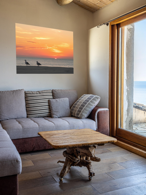 Living room with a gray sofa, wooden coffee table, and a canvas print of two seagulls standing on a sandy Jersey Shore beach during a vibrant orange sunrise over the Atlantic Ocean