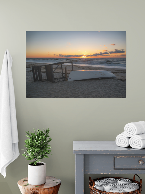 Canvas print of a Jersey Shore sunrise on a wall above a table with towels and a plant.