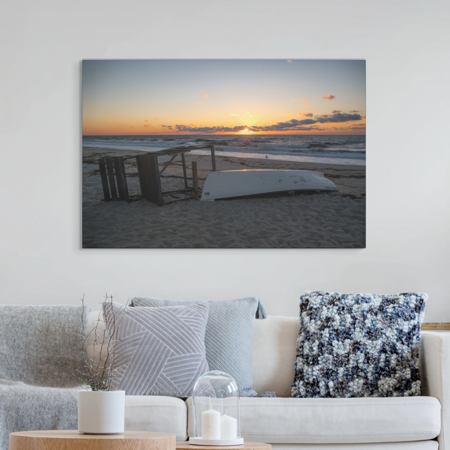 Canvas print of a Jersey Shore sunrise on a wall above a sofa with decorative pillows.