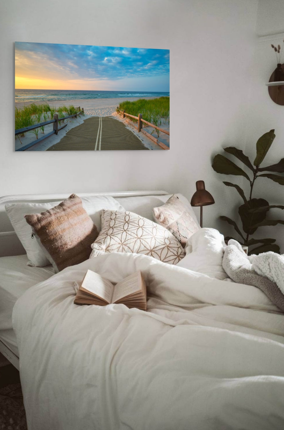 Bedroom with a bed, pillows, and a canvas print of a beach path on the Jersey Shore shortly after sunrise over the ocean on the wall.