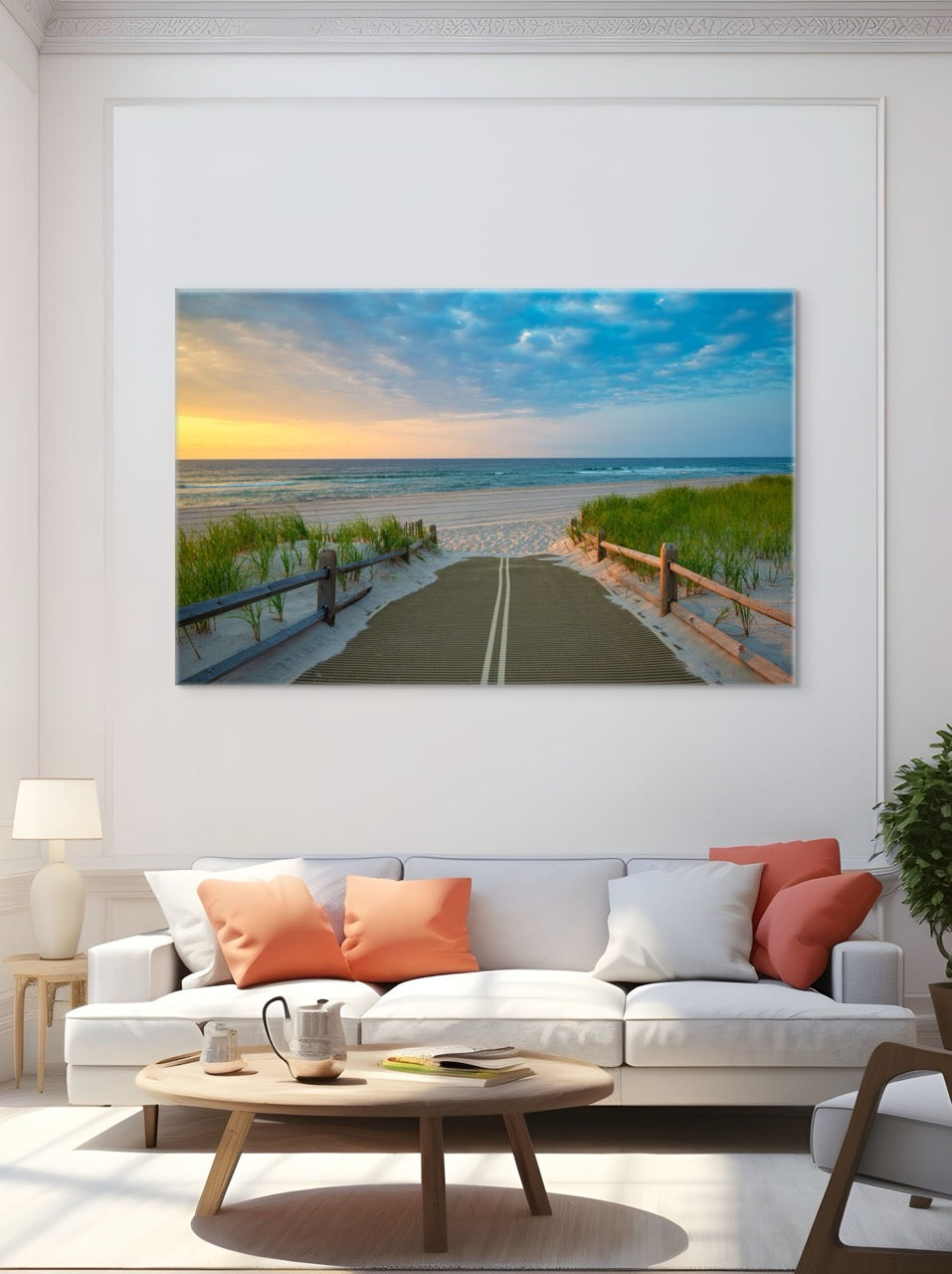 A canvas print of a beach path on the Jersey Shore shortly after sunrise over the ocean above a white sofa with orange and white cushions in a living room.