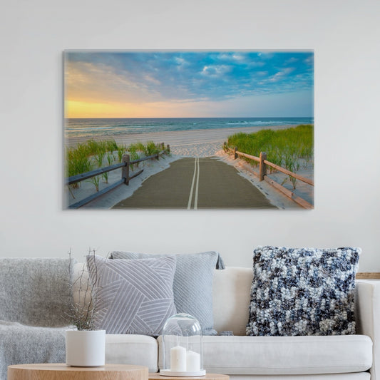 A canvas print of a beach path on the Jersey Shore shortly after sunrise over the ocean above a sofa with decorative pillows