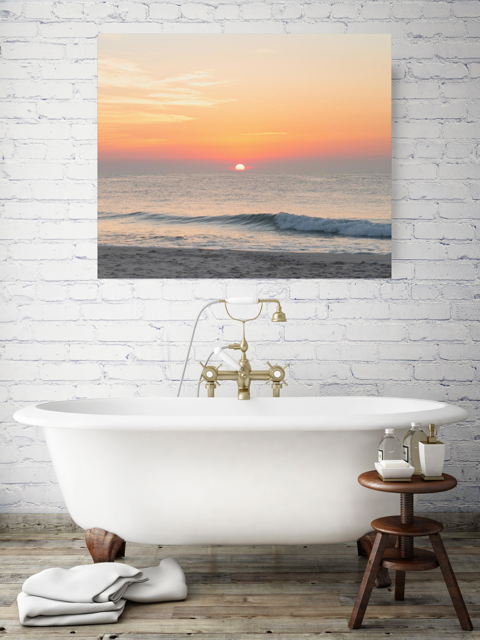 Bathroom with a freestanding bathtub and a canvas print featuring a summer sunrise over the Atlantic Ocean as seen from a quiet beach on the Jersey Shore on the wall.