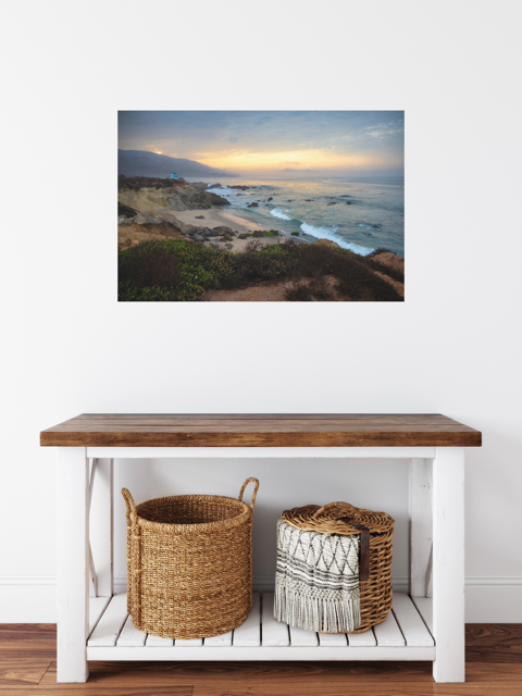 Wooden bench with woven baskets against a wall featuring a canvas print of the sunrise over the mountains as seen from the cliffs of Leo Carrillo State Beach near Malibu, California