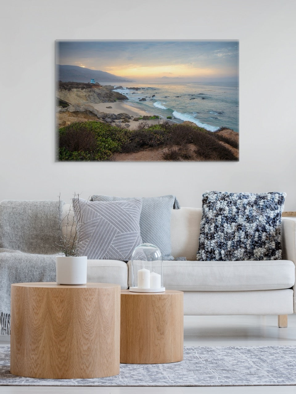 Living room with a couch, coffee table, and wall art of a canvas print of the sunrise over the mountains as seen from the cliffs of Leo Carrillo State Beach near Malibu, California.