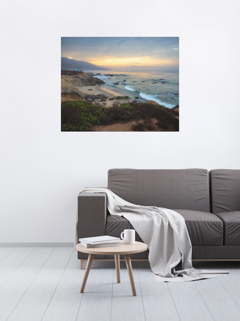 Living room with a gray sofa, small round table, and a large canvas print of the sunrise over the mountains as seen from the cliffs of Leo Carrillo State Beach near Malibu, California.