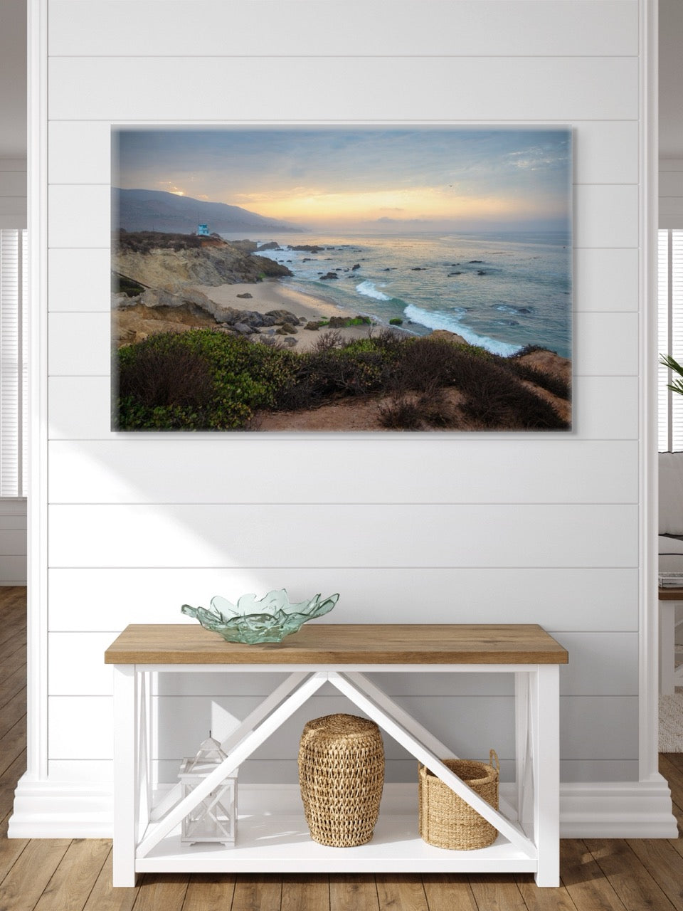 Canvas print of the sunrise over the mountains as seen from the cliffs of Leo Carrillo State Beach near Malibu, California. on a wall above a wooden bench with storage.