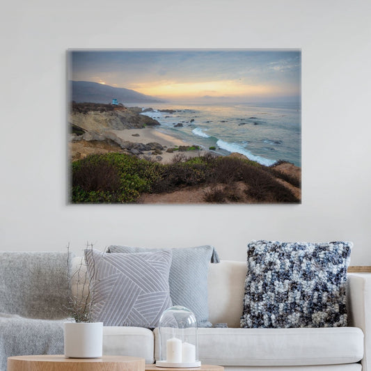 A canvas print of the sunrise over the mountains as seen from the cliffs of Leo Carrillo State Beach near Malibu, California above a living room sofa with decorative pillows and candles.