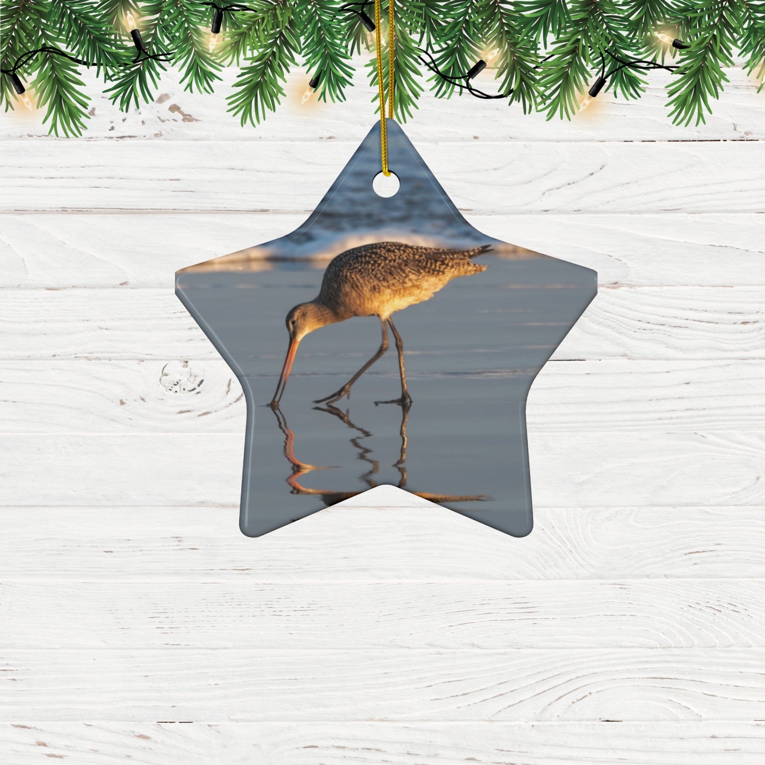 Star-shaped ceramic holiday ornament featuring a photograph of a Long-billed Curlew mirrored in the wet sand of a shoreline under a soft golden sun