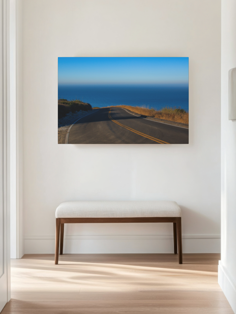 Canvas print of a winding mountain road above the Pacific Ocean in Malibu California, placed above a wooden bench.