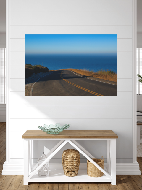 Canvas print of a winding mountain road above the Pacific Ocean in Malibu California hanging above a wooden bench with storage.