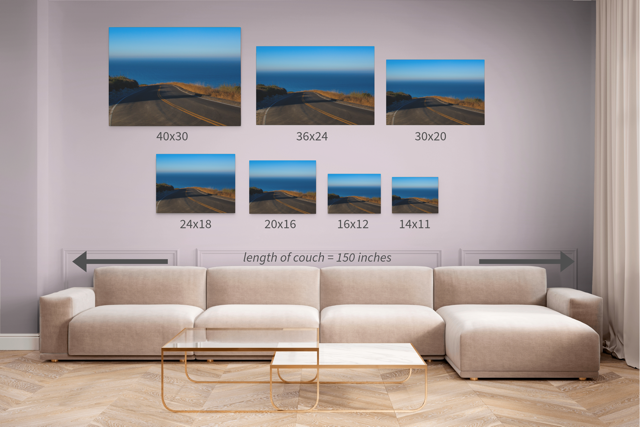 Wall art prints of a scenic road with ocean view displayed above a sofa in various sizes.