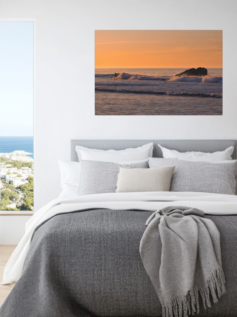Bedroom with a lcanvas print featuring a surfer riding a wave at sunrise above the bed.
