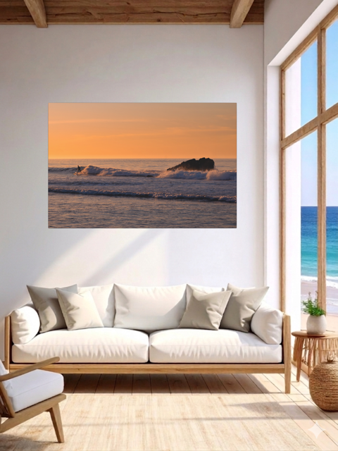 Living room with a canvas print featuring a surfer riding a wave at sunrise on the wall, white sofa, and large window.