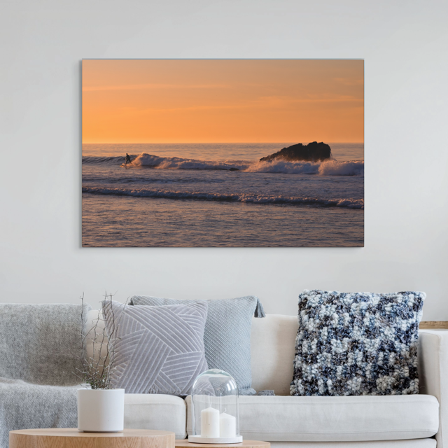 Living room with a lcanvas print featuring a surfer riding a wave at sunrise.