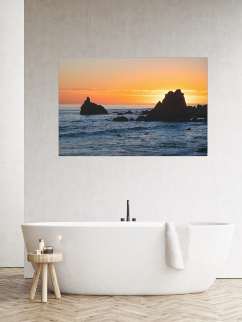 Bathroom with a canvas print of an ocean sunset with rocks.