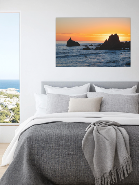 Bedroom with a canvas print of an ocean sunset with rocks.