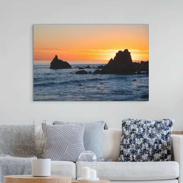 Living room with a canvas print of an ocean sunset with rocks.