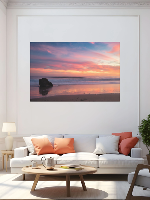 Living room with a canvas print of a solitary rock sea stack on a Malibu beach at sunset with a vibrant pink, orange, and purple sky reflected in the wet sand on the wall.