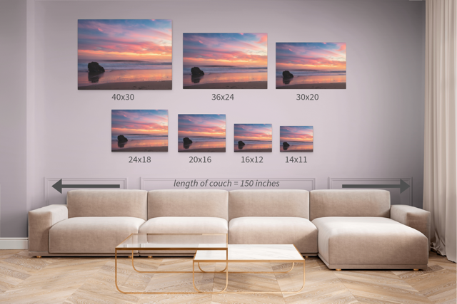 Living room with a beige sectional sofa and seven different sizes of a canvas print of a solitary rock sea stack on a Malibu beach at sunset with a vibrant pink, orange, and purple sky reflected in the wet sand.
