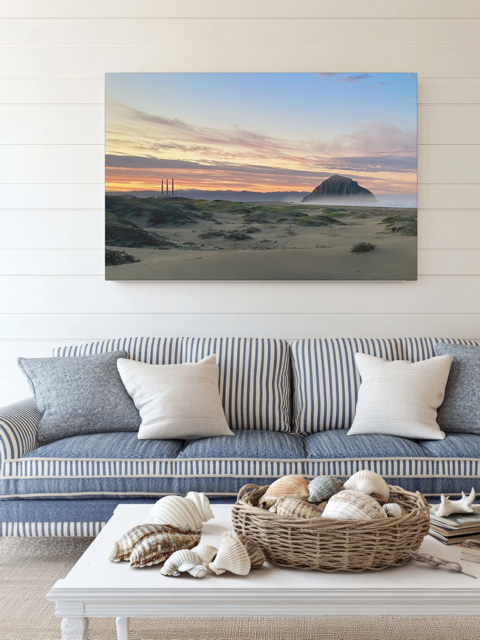 Living room with a couch, coffee table, and a vibrant sunrise over Morro Rock and Three Stacks from beach dunes canvas printon the wall.
