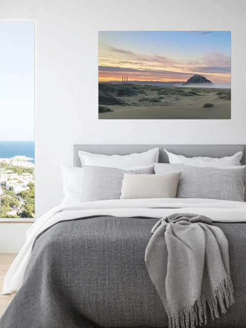 Bedroom with a vibrant sunrise over Morro Rock and Three Stacks from beach dunes canvas print above the bed.