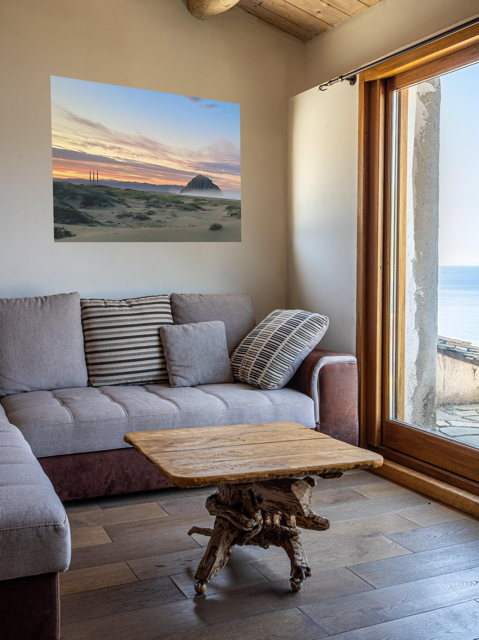 Living room with a gray sofa, wooden coffee table, and a vibrant sunrise over Morro Rock and Three Stacks from beach dunes canvas print.