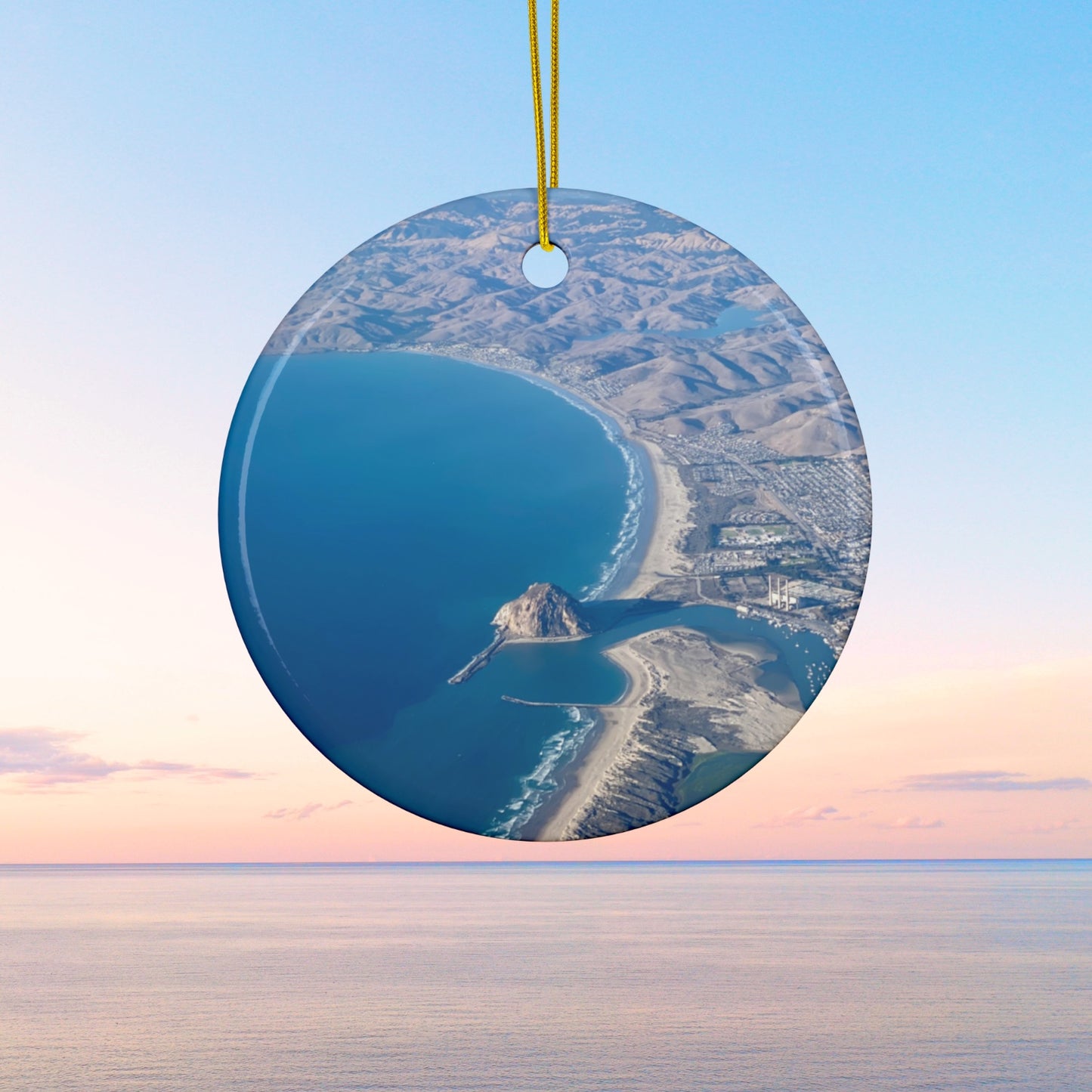Ceramic holiday ornament featuring an aerial photograph of Morro Rock and the coastline of Morro Bay, California, with vibrant blue water and golden hills