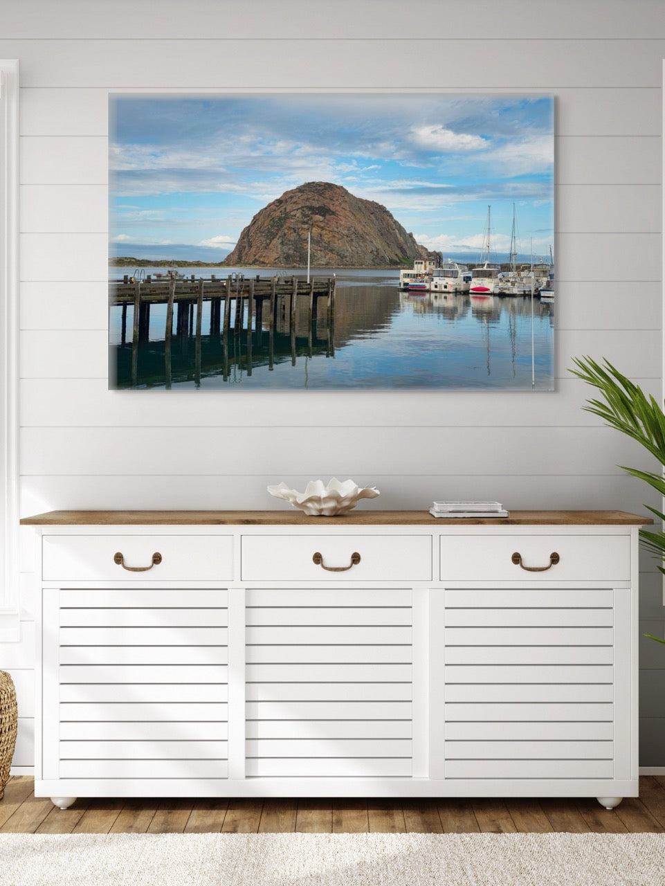 White cabinet with wooden top below a large canvas print featuring a view of Morro Rock from the harbor in Morro Bay, California with boats and a pier.