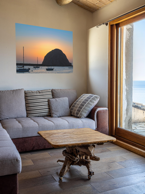 Living room with a gray sofa, wooden coffee table, and a canvas print of a Morro Rock sunset with sailboats.